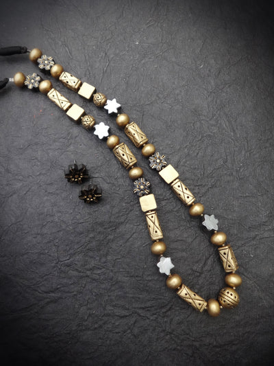 Decorative necklace with gold and bronze beads on a dark textured surface